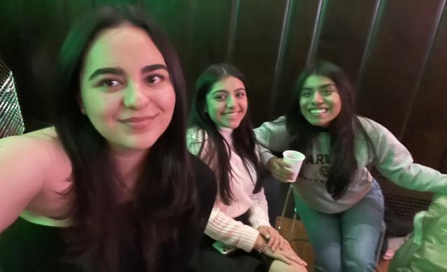 Three students are seated to take a picture. They are at a social event. 