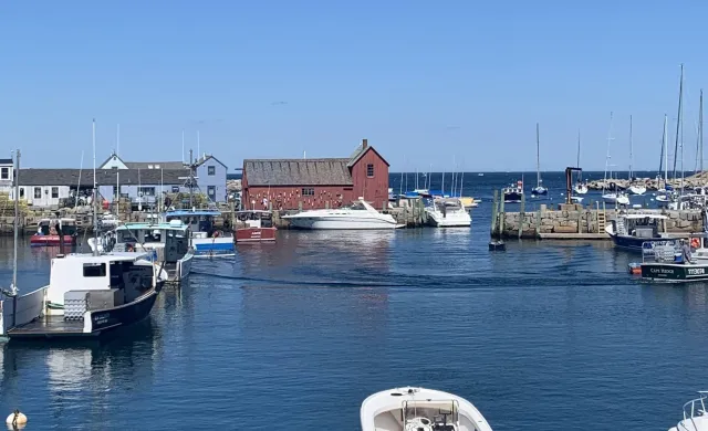 A red farmhouse surrounded by water and boats.