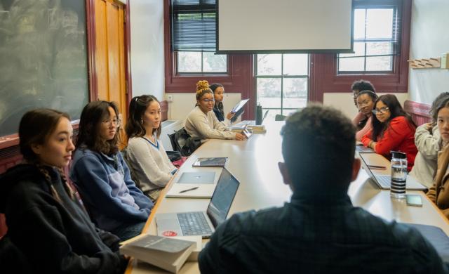 students and professors sitting around a table having a discussion