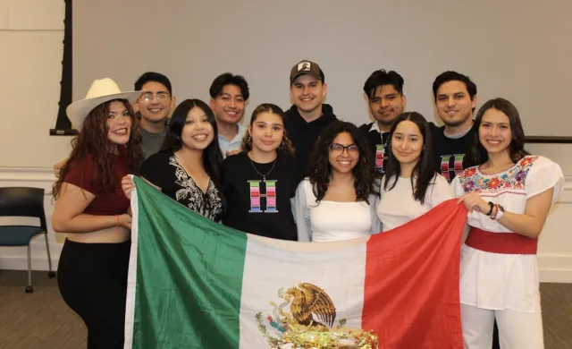 An image of the 11 board members for RAZA of the 2023 year.  They are holding up a Mexican flag. 