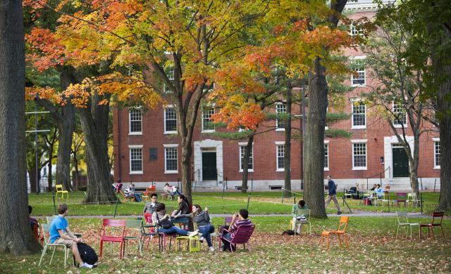 Image of students sitting on grass in front of building 