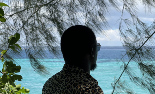 A photo of a man in sunglasses looking at blue ocean waters.