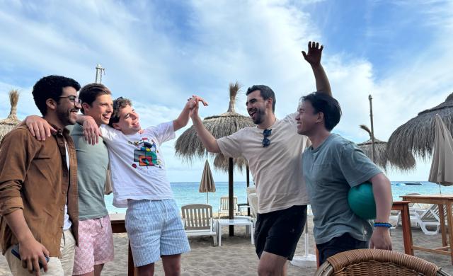 Group of 5 friends standing in front of the beach at Ibiza, Spain.