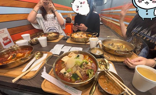 Five individual hot pot soups are pictured at a table.