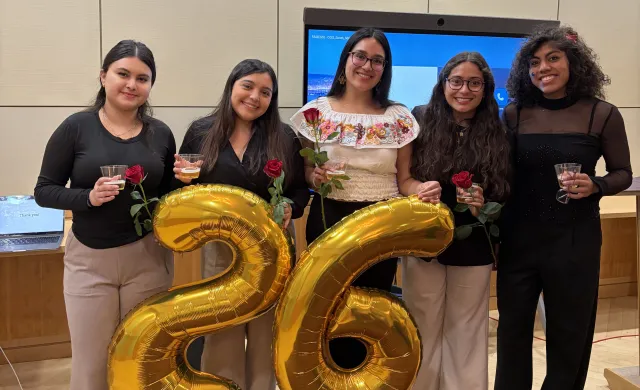 Lizbeth and four friends who just presented at the Latinx Senior Thesis Forum pose for a photo. Each person is holding a red rose.