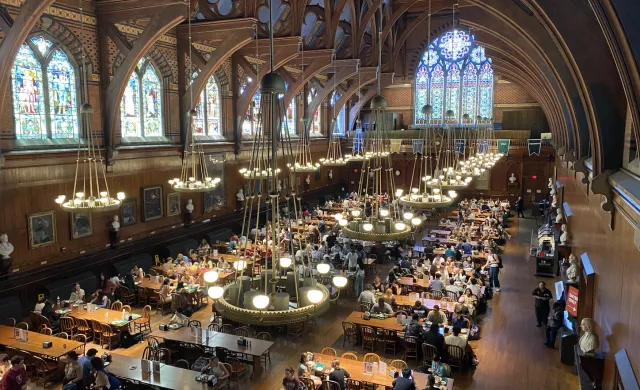 Indoor dining hall with rows of dining tables and stained glass windows