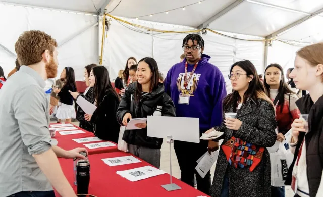 Visitas Concentration Fair 2024. Students lined up at table listening to a concentration advisor.