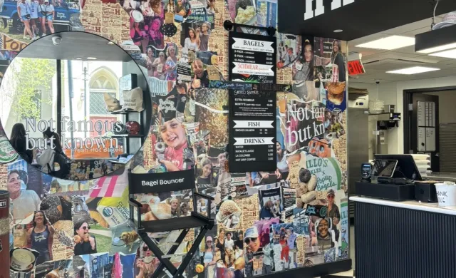 Inside of a bagel shop with a collage of picture, a mirror, and checkered floor tiles