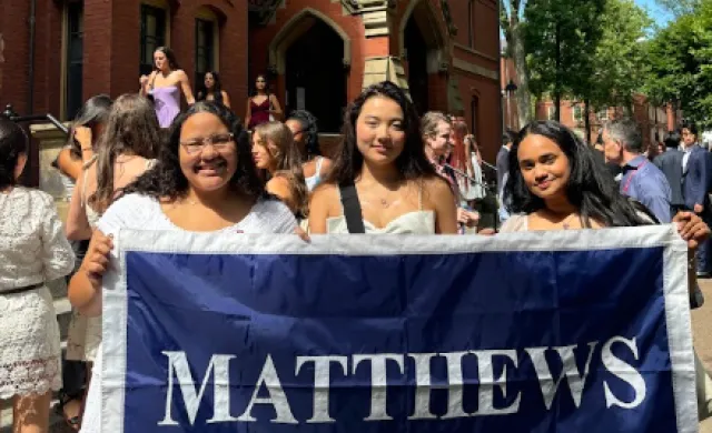 Three roommates holding their first-year dorm flag.