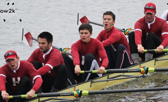 Students in crimson colored shirts rowing a boat