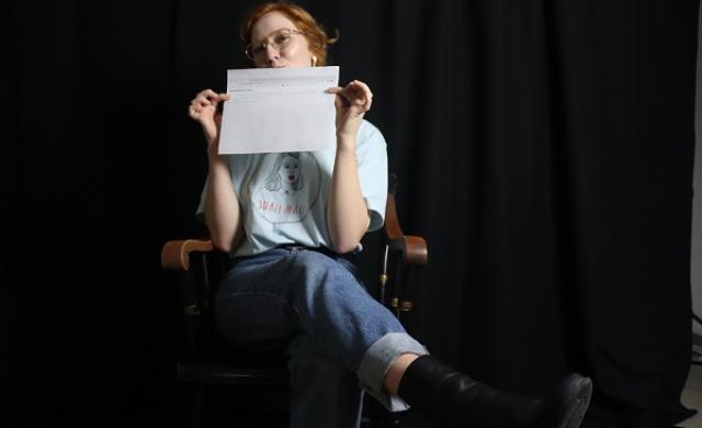 student in a chair and holding a piece of paper