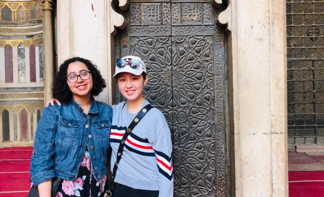 Two students in front of a mosque