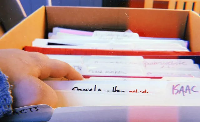 Hand going through files in a box at an archive 