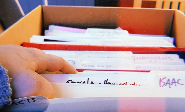 Hand going through files in a box at an archive 
