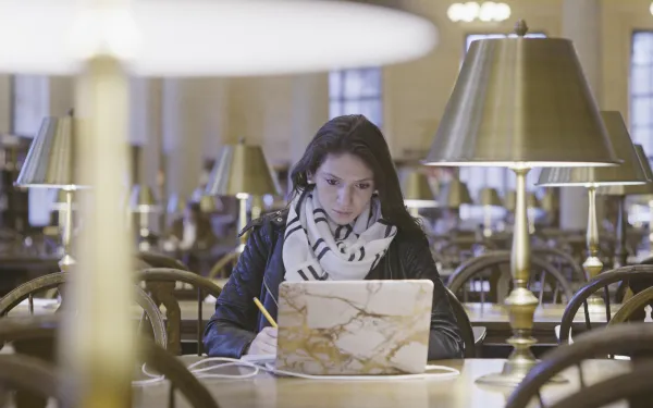 Female student working at a laptop in Widener library 