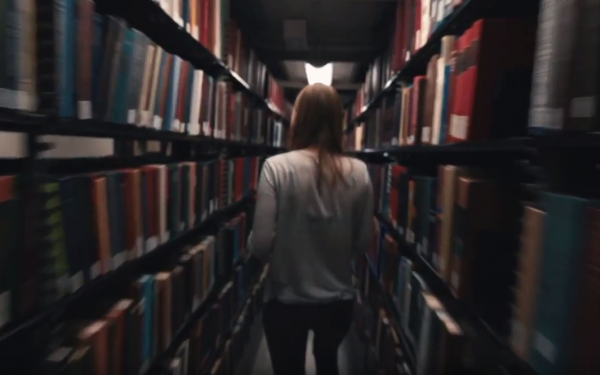 Student walking through library stacks