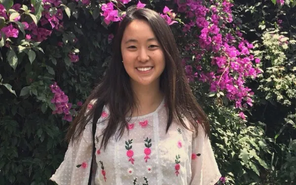 Student standing in front of flowers.