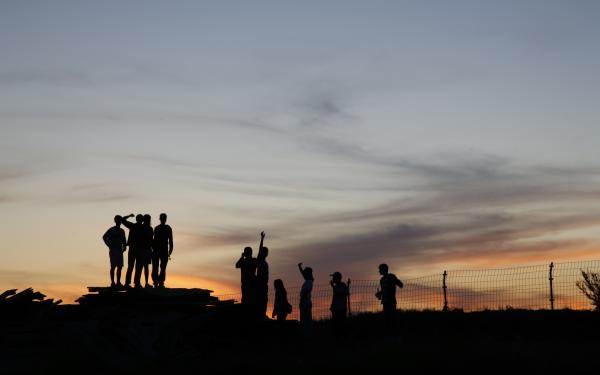Silhouette of a group of people against a sunset background