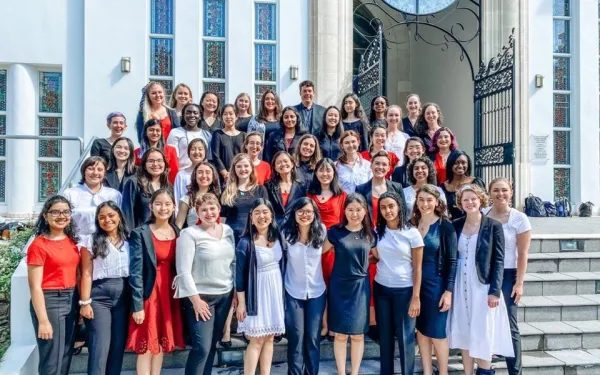Members of the Radcliffe Choral Society standing on the steps of a church, in formal concert wear.