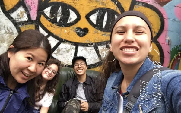 4 students in front of wall art in Paris.