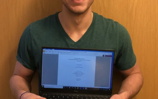 Student Holding a laptop in front of him