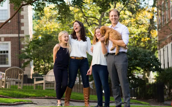 A portrait of Janine Santimauro and David Deming, faculty deans of Kirkland House, with their two daughters and dog.