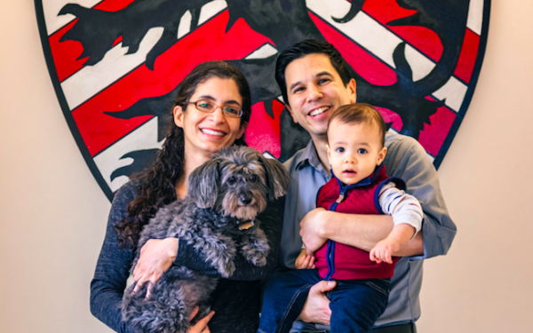 A portrait of Kiran Gajwani and Stephen Chong, faculty deans of Winthrop House, with their son and dog.