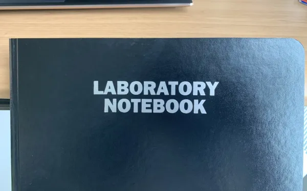 A black notebook with the words "LABORATORY NOTEBOOK" in white at the center.