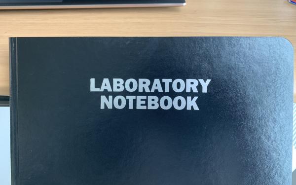 A black notebook with the words &quot;LABORATORY NOTEBOOK&quot; in white at the center.