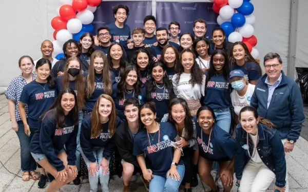 group of students in matching IOP t-shirts in front of red, white, and blue balloons