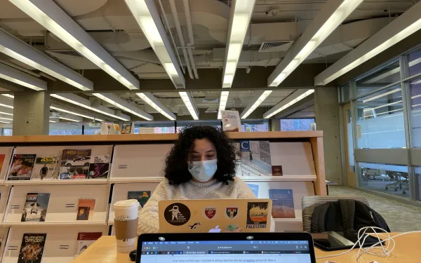 Student typing on computer in a common study space
