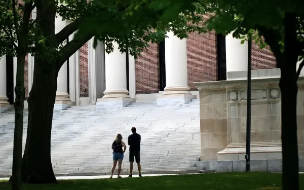 Silhouette of two people standing in front of Widener steps