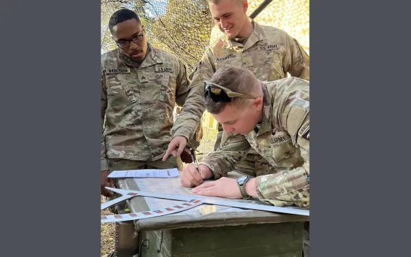 Three men look at papers on a table, including Henry Sullivan Atkins '20