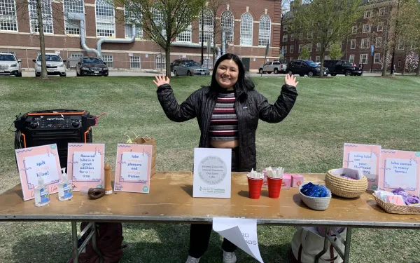 A girl standing behind a table with her hands outstretched.