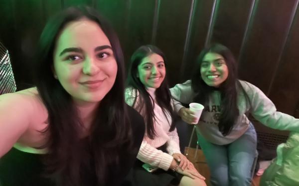 Three students are seated to take a picture. They are at a social event. 
