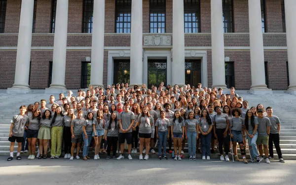 A large group of students gather in front of a library to pose for a picture. 