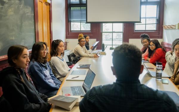 masters with thesis or without students and professors sitting around a table having a discussion