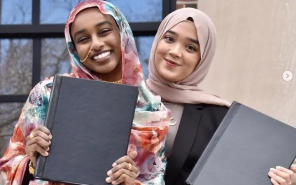 Two women show off senior thesis booklets