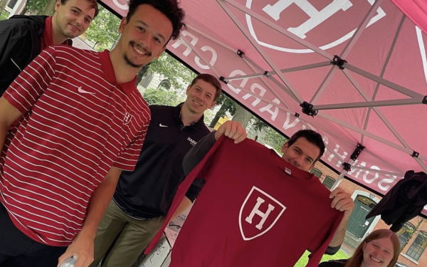 Students in move in tent holding up Harvard sweater