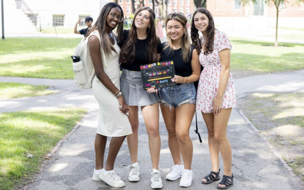 Four women pose with first day of school chalkboard