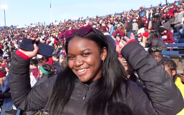 A student cheering in the crowd of a football stadium.