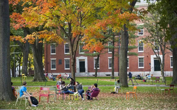 Image of students sitting on grass in front of building 