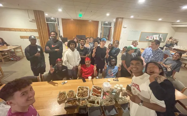 Studens gathered around a table full of food 