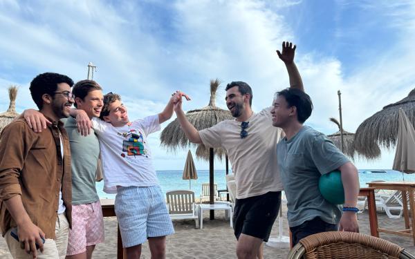 Group of 5 friends standing in front of the beach at Ibiza, Spain.