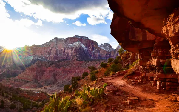 A picture of the Watchman Trail with the setting sun and snow-capped mountains in the background.