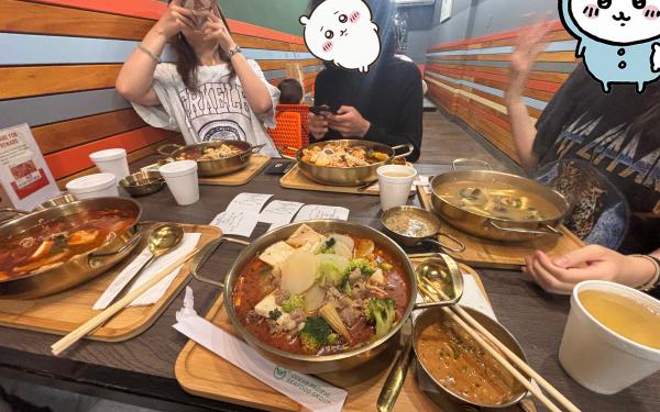 Five individual hot pot soups are pictured at a table.