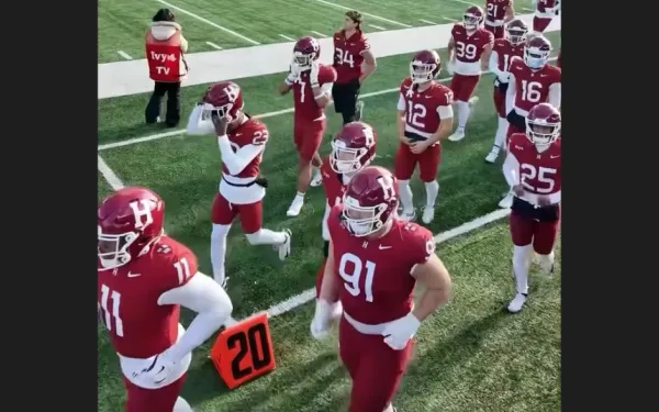 Harvard football players in red uniforms walking on the field.