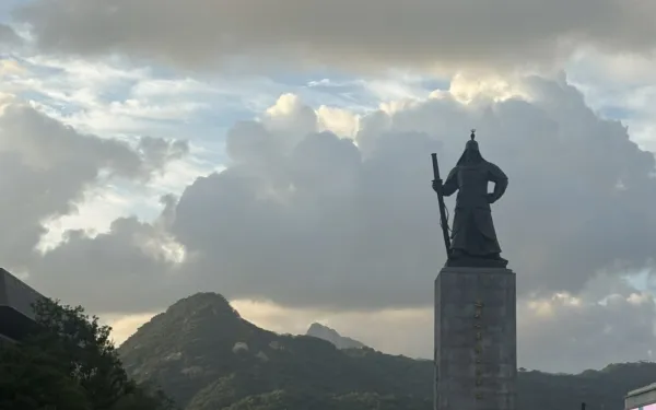 Picture of a plaza in the afternoon with a statue and people walking around
