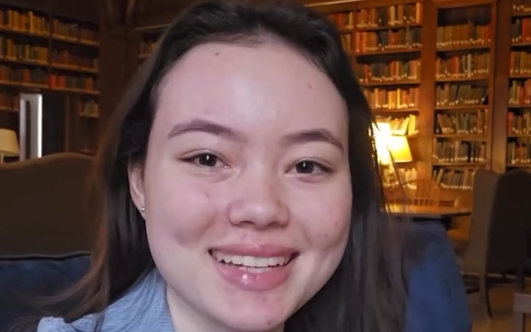 Student smiles in a wood-paneled library with bookshelves