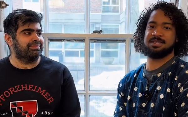 Two students sit by a window, one wearing a Pforzheimer House sweatshirt, talking together.